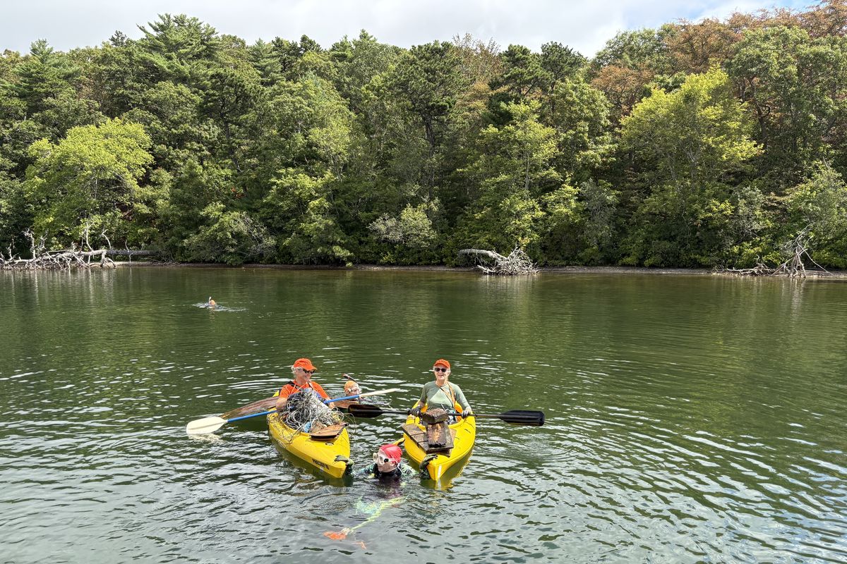 Divers and kayakers from the group Old Ladies Against Underwater Garbage collect trash in Johns Pond in Mashpee, Massachusetts.