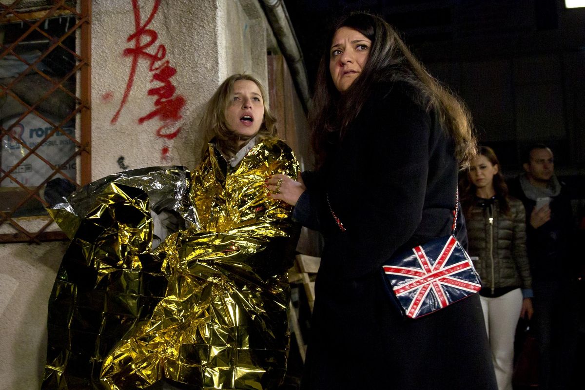 A survivor of an explosion that occurred in a club in Bucharest, is led away from the blast scene wrapped in a thermal blanket early Saturday. (Vadim Ghirda / Associated Press)