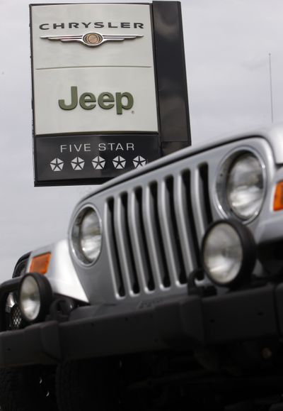 A Chrysler-Jeep sign hangs over the hood of an 2009 Jeep Wrangler at a Chrysler-Jeep dealership in Centennial, Colo.  (File Associated Press / The Spokesman-Review)
