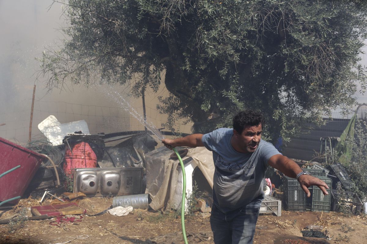 A man holding a garden hose shouts to someone as flames from a wildfire reach the backyard of a house in the town of Macao, central Portugal, Thursday, Aug. 17 2017. Portugal’s government is taking the rare step of decreeing a state of public calamity ahead of a forecast rise in temperatures that authorities fear will worsen a spate of wildfires. (Armando Franca / Associated Press)