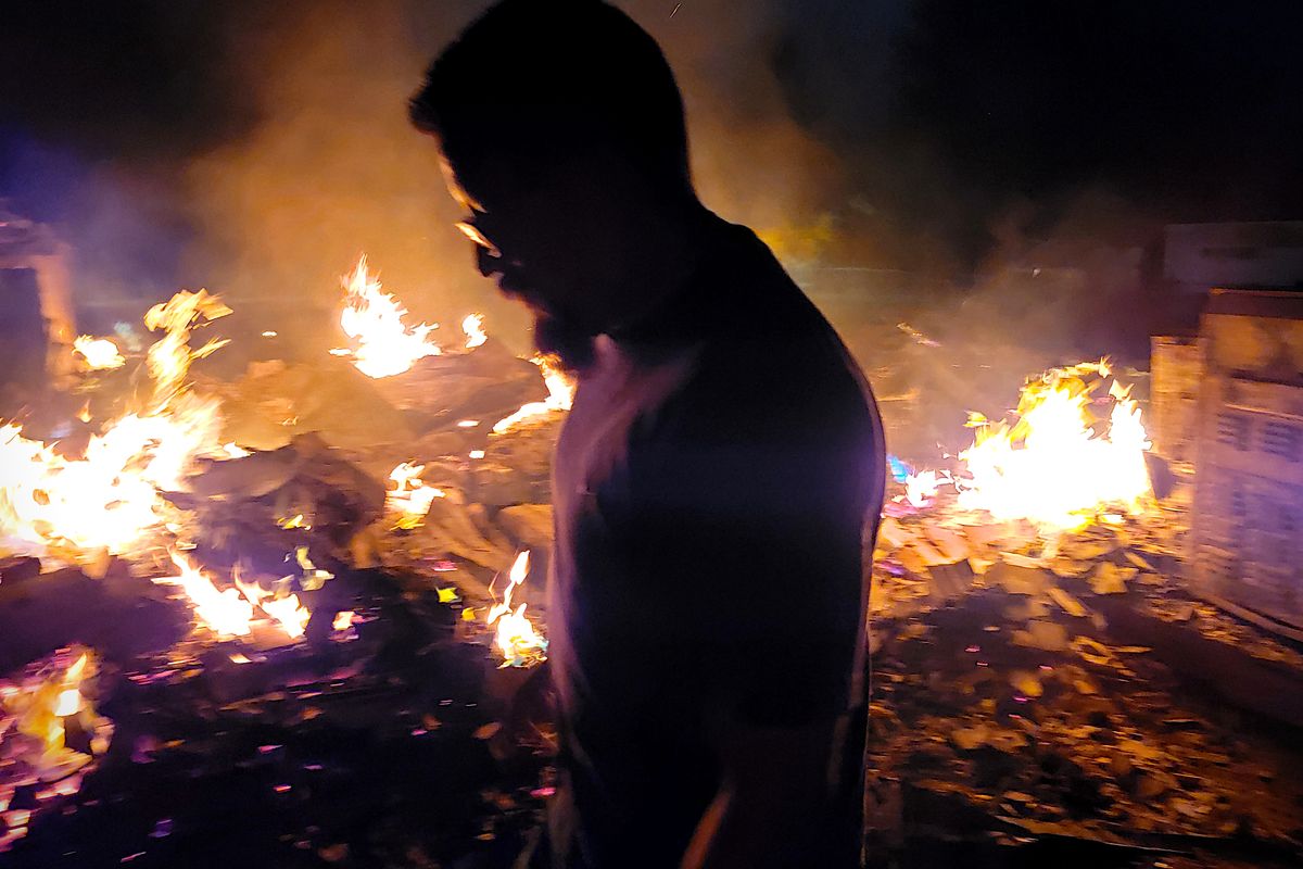 Isaiah Tonasket looks at the burning rubble of his family