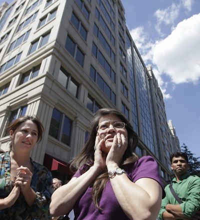 Susy Ward, center, and other office workers gather on the sidewalk in downtown Washington, D.C., moments after an earthquake on Tuesday. (Associated Press)