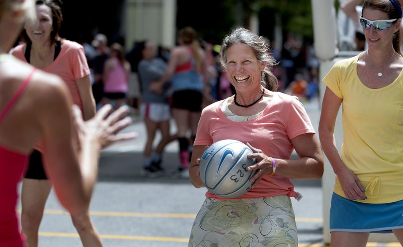 Amy Bogaard, center, of the Vashon Island Rock Lobsters, smiles at her opponent before checking the ball during their game against The Gone Girls on Post Street. The 25th edition of Hoopfest kicked off Saturday morning in downtown Spokane with nearly 27,000 players among 6,900 teams on 42 city blocks. (Kathy Plonka)