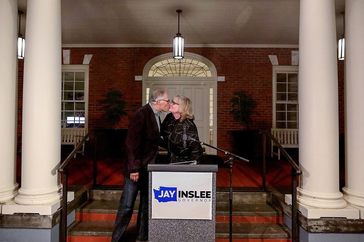 Gov. Jay Inslee kisses his wife Trudi after she introduced him following the Associated Press declaring him a winner for a third consecutive term. This on the porch of an official residence on Tuesday, Nov. 3, 2020.   (Alan Berner/The Seattle Times via Associated Press)