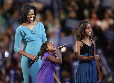 As her mother, Michelle, and sister, Malia, 10, watch, Sasha Obama, 7, blows a kiss to her dad Monday as he addresses the Democratic convention via satellite from Kansas City.  (Associated Press / The Spokesman-Review)