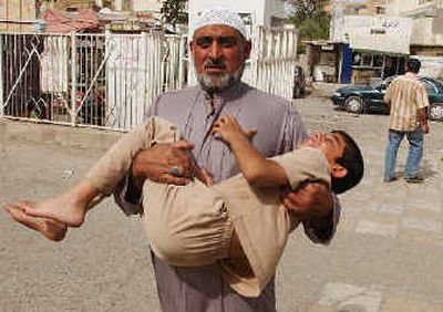 
A man carries a child to the hospital after the boy was injured during the explosion of a car bomb at a Shiite mosque Friday in Baghdad, Iraq. The blast killed eight people and wounded 26 during midday prayers. 
 (Associated Press / The Spokesman-Review)