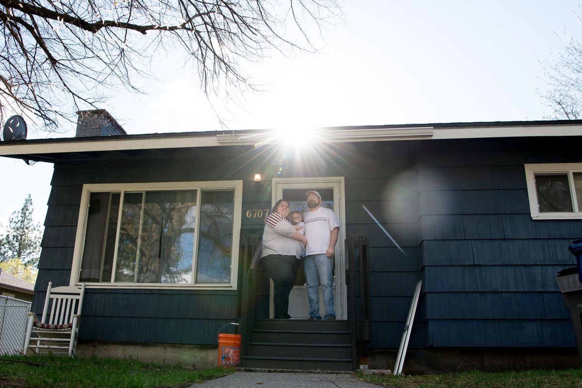 Micah and Katie Blake stand on the porch of their  home with their daughter Rylee on Wednesday, April 17. The Blakes were turned down multiple times by sellers before striking luck, buying their first home north of Francis Avenue. (Tyler Tjomsland / The Spokesman-Review)