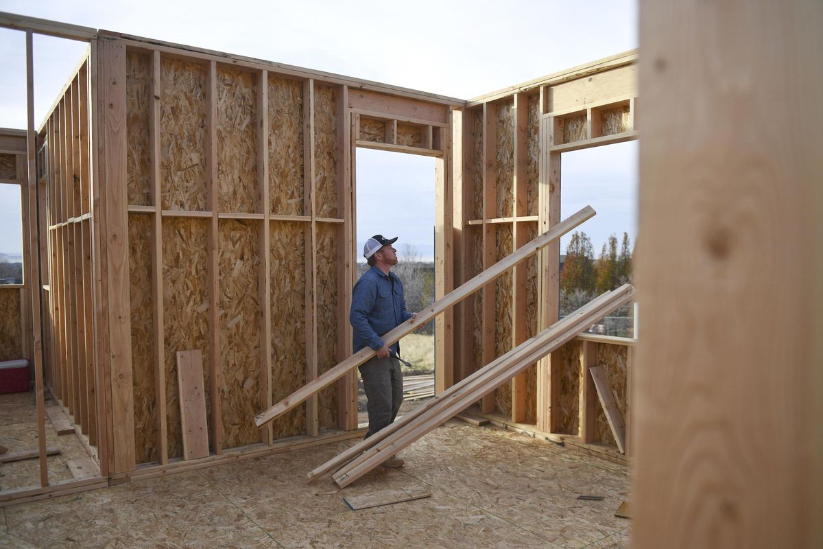 Dustin Brinkerhoff, owner of Brinkerhoff Custom Construction, walks with boards to put in place as a temporary safety guard rail at a worksite of a future home in Mapleton, Utah, on Nov. 10, 2017. (Associated Press)