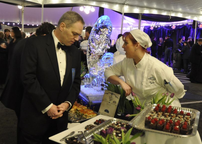 OLYMPIA -- State Rep. Ross Hunter gets advice on an appetizer selection from Kyla Applegate of Skagit Valley College at the food tent for the Inaugural Ball. (Jim Camden)