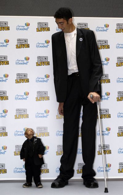 He Pingping of China, 21, left, and Sultan Kosen of Turkey, 27, are seen during an event organized by Guinness World Records in Istanbul, Turkey, on Thursday. Kosen is the tallest man walking the planet with a height of 8 feet, 1 inch, and He is officially the world’s shortest man with a height of 2 feet, 5 inches. (Associated Press)