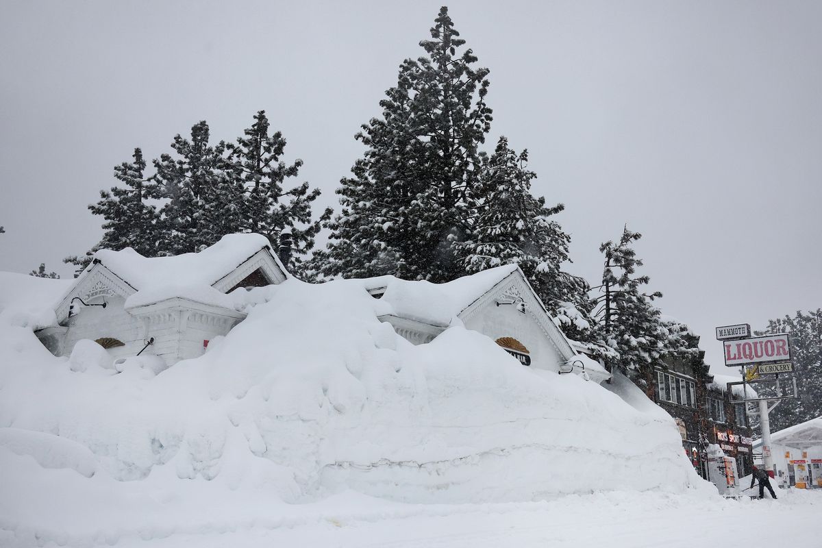 Brian Dunham shovels snow near snowbanks piled up from previous storms during another winter storm in the Sierra Nevada mountains on Friday in Mammoth Lakes, California.  (Mario Tama/Getty Images North America/TNS)