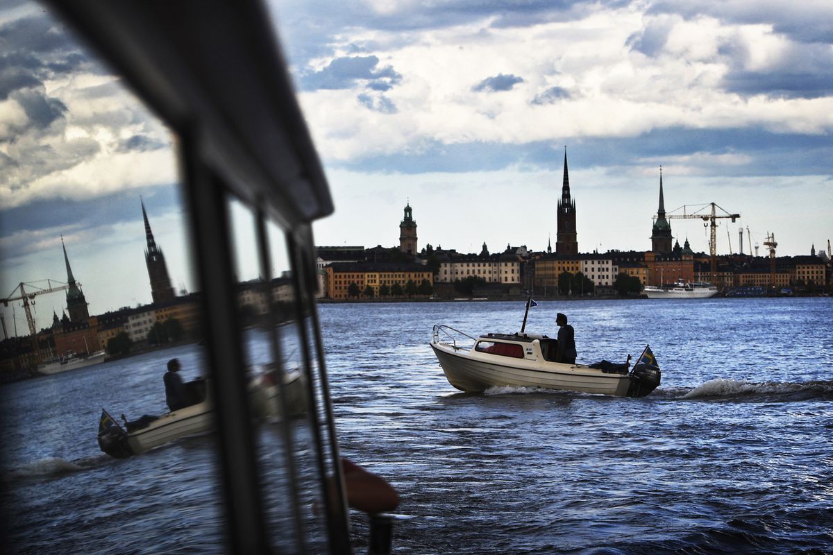 A passing boat and Stockholm’s Old Town are seen reflected in the window of a ferry during a water tour of the city.