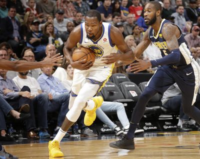 Golden State’s Kevin Durant (center) drives past Denver’s Will Barton during Saturday’s game. (Jack Dempsey / Associated Press)