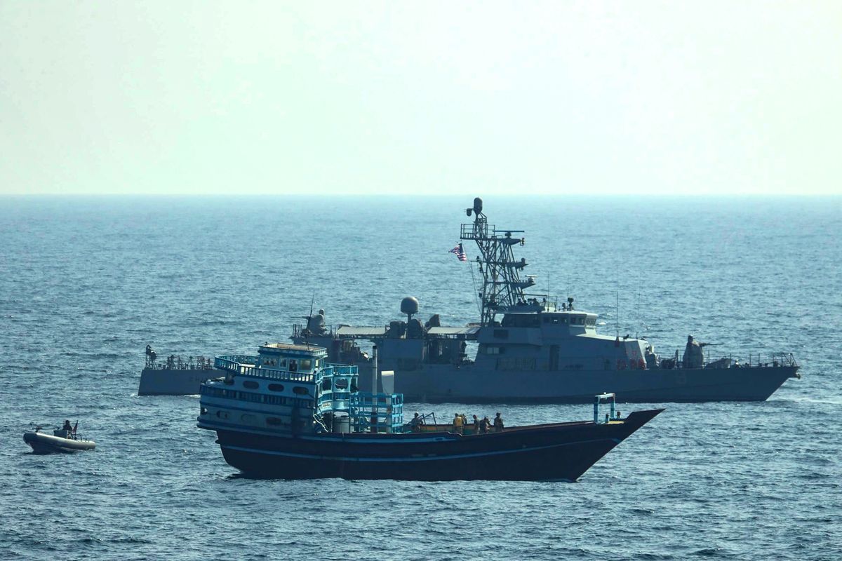 This photo released by the U.S. Navy, shows U.S. service members conduct a boarding on a stateless fishing vessel transiting international waters in the Gulf of Oman as a rigid-hull inflatable boat and patrol coastal ship USS Chinook (PC 9) sail nearby, Tuesday, Jan. 18, 2022. The U.S. Navy announced Sunday, Jan. 23 that it seized the boat in the Gulf of Oman carrying fertilizer used to make explosives that was caught last year smuggling weapons to Yemen.  (HOGP)