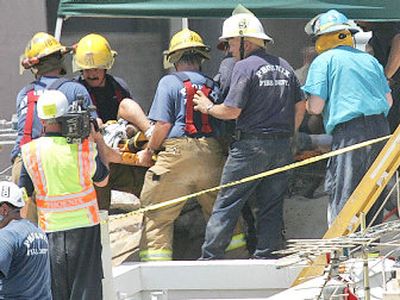 
Firefighters and rescuers rush a 28-year-old construction worker to an ambulance moments after he was pulled from a collapsed Phoenix parking garage  on  Tuesday. 
 (Associated Press / The Spokesman-Review)