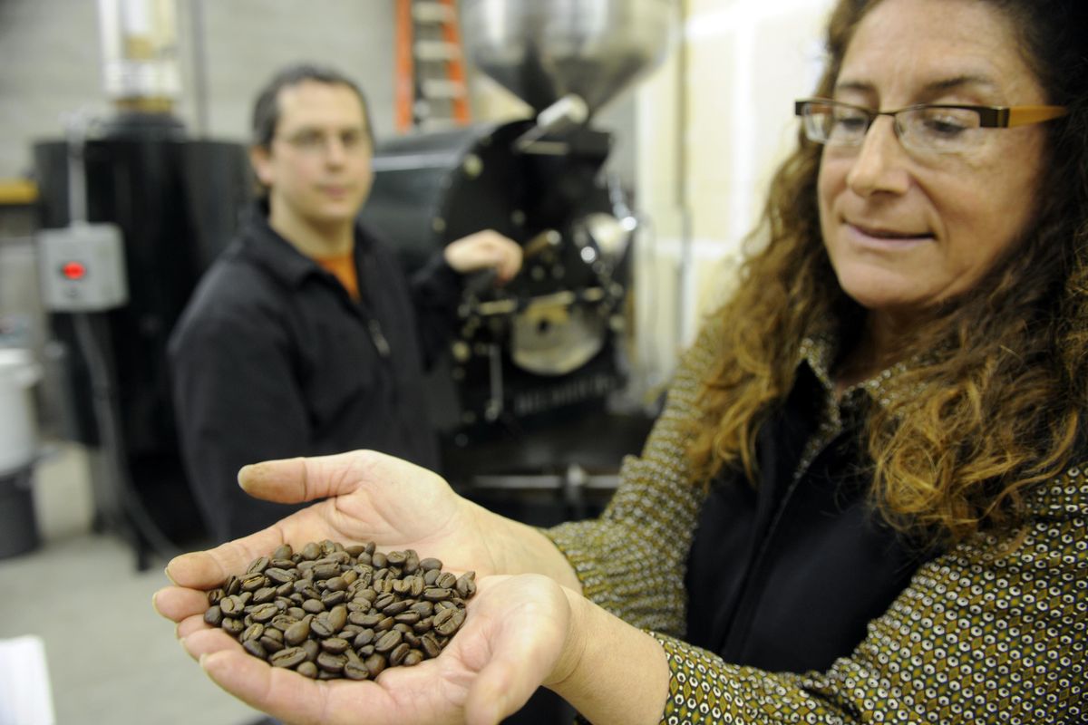 Deborah Di Bernardo holds a handful of coffee beans recently roasted by Dave Rier, left, at Roast House Coffee in this file photo from 2010. (Jesse Tinsley / The Spokesman-Review)