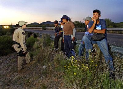 
A U.S. Border Patrol agent,  left, speaks with a group of illegal immigrants after they gave up their trek into the United States in Topawa, Ariz., in 2004.  
 (File/Associated Press / The Spokesman-Review)