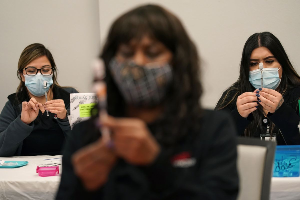 FILE - In this Jan. 22, 2021, file photo, certified medical assistants Martha Sida, from left, Tina Killebrew and Cynthia Bernal prepare doses of the Pfizer-BioNTech COVID-19 vaccine at a vaccination center at the University of Nevada, Las Vegas, in Las Vegas. COVID-19 vaccine makers tell Congress to expect a big jump in the delivery of doses over the coming month. The companies insisted Tuesday, Feb. 23, at a hearing that they will be able to provide enough vaccine for most Americans by summer.  (John Locher)