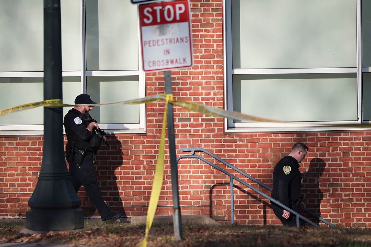 Law enforcement personnel move through the crime scene where three people were killed and two others wounded on the grounds of the University of Virginia on Nov. 14, 2022, in Charlottesville, Va. The suspect is believed to be a student at the university and is still at large as the campus remains in a shelter in place lockdown. (Win McNamee/Getty Images North America/TNS)