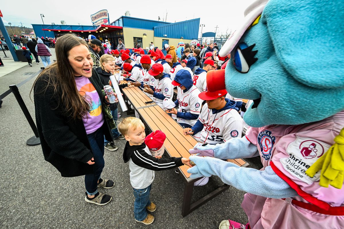 After having his hat and baseball signed by the entire Spokane Indians baseball team, Wyatt Davis, 5, hands Doris the Spokansaurus mascot his ball for her to autograph Wednesday during the Spokane Indians Fan Fest at Avista Stadium. Behind Wyatt is his mom Brianne Davis.  (COLIN MULVANY/THE SPOKESMAN-REVIEW)