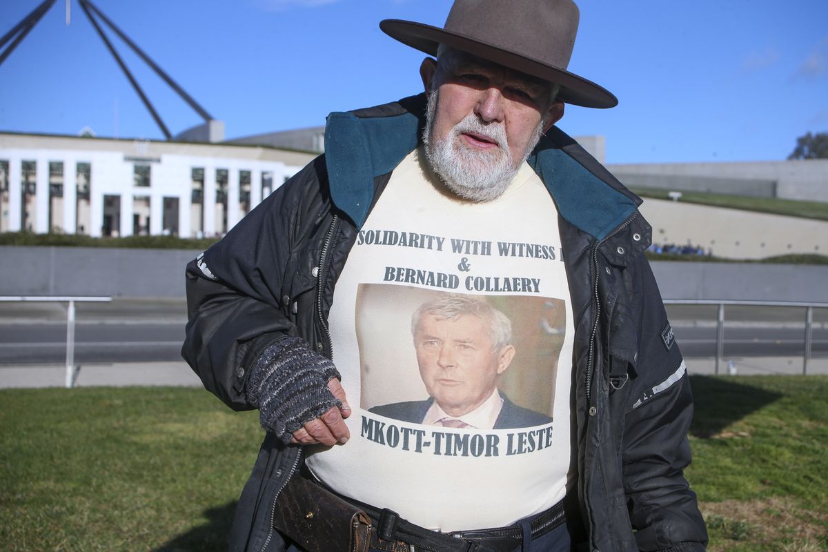 Demonstrator Dierk von Behrens protests outside Parliament House in Canberra, Australia, Thursday, June 17, 2021 against the prosecution of lawyer Bernard Collaery whose picture is on the demonstrator
