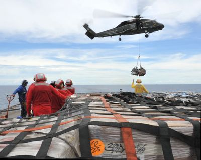 In this photo released by the U.S. Navy, sailors aboard the USS Blue Ridge in the South China Sea stand by Saturday to move pallets of relief supplies ready to assist in Japan. (Associated Press)