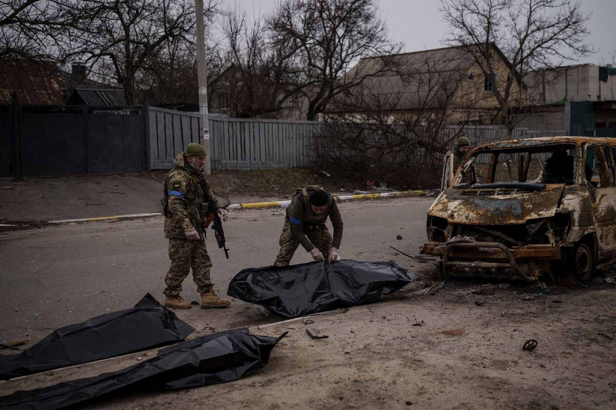 Ukrainian soldiers recover the remains of four killed civilians from inside a charred vehicle in Bucha, outskirts of Kyiv, Ukraine, Tuesday, April 5, 2022. Ukraine’s president plans to address the U.N.’s most powerful body after even more grisly evidence emerged of civilian massacres in areas that Russian forces recently left.  (Felipe Dana)