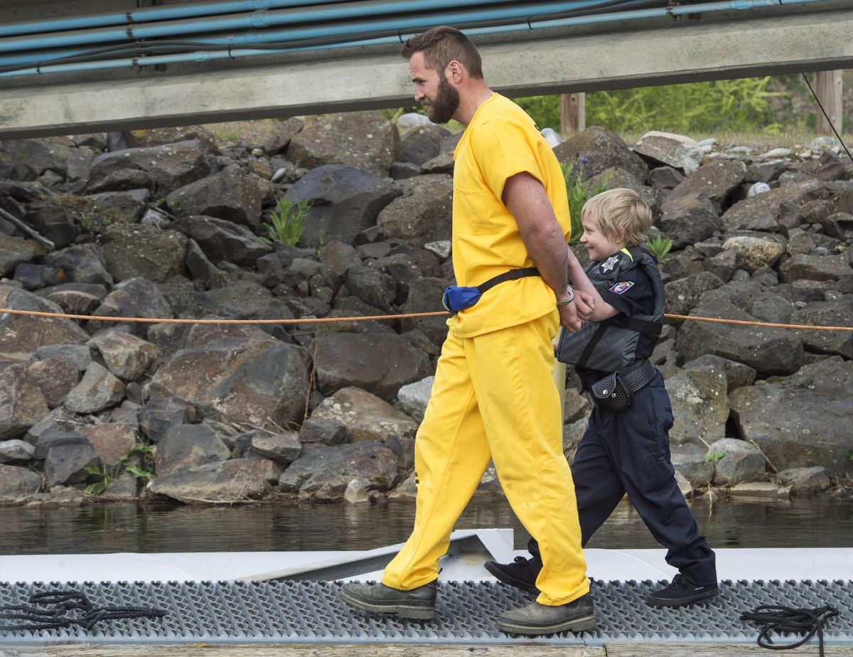 Sierra Shank escorts an escaped convict (police officer Christopher Brasch) to a police car after his capture on the banks of the Spokane River. (Dan Pelle / The Spokesman-Review)