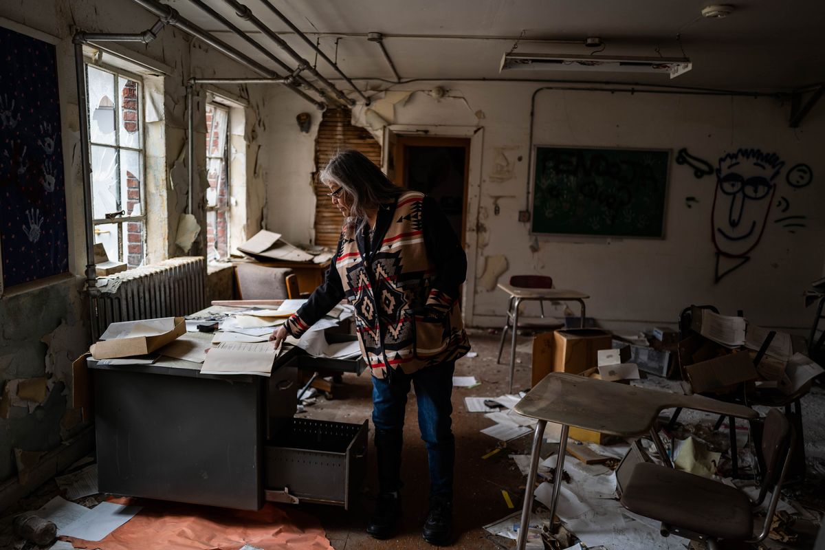 Clarita Vargas, one of the survivors of St. Mary’s Mission, an Indian boarding school, looks through old books as she walks through the school building in Omak, Wash., in February.  (Salwan Georges/The Washington Post)