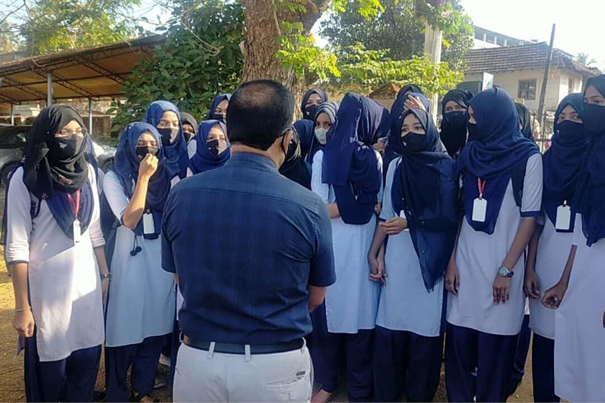Indian girl students who were barred from entering their classrooms for wearing hijab, a headscarf used by Muslim women, speak to their principal outside the college campus in Udupi, India, Friday, Feb. 4, 2022. Muslim girls wearing hijab are being barred from attending classes at some schools in the southern Indian state of Karnataka, triggering weeks of protests by students.  (Bangalore News Photos)