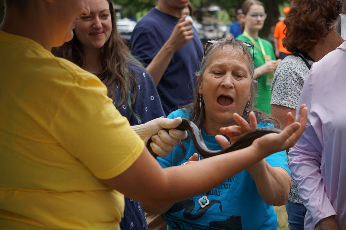 Yakama Nation Fisheries staff encouraged attendees of the 5th annual Yakama Nation Lamprey Celebration to try touching the eel-like fish. The event held Thursday along the Willamette River in Oregon City, Ore., brought out hundreds of people. Pacific lamprey are an ancient and culturally significant species for many Northwest tribes.  (Alex Baumhardt/Oregon Capital Chronicle)