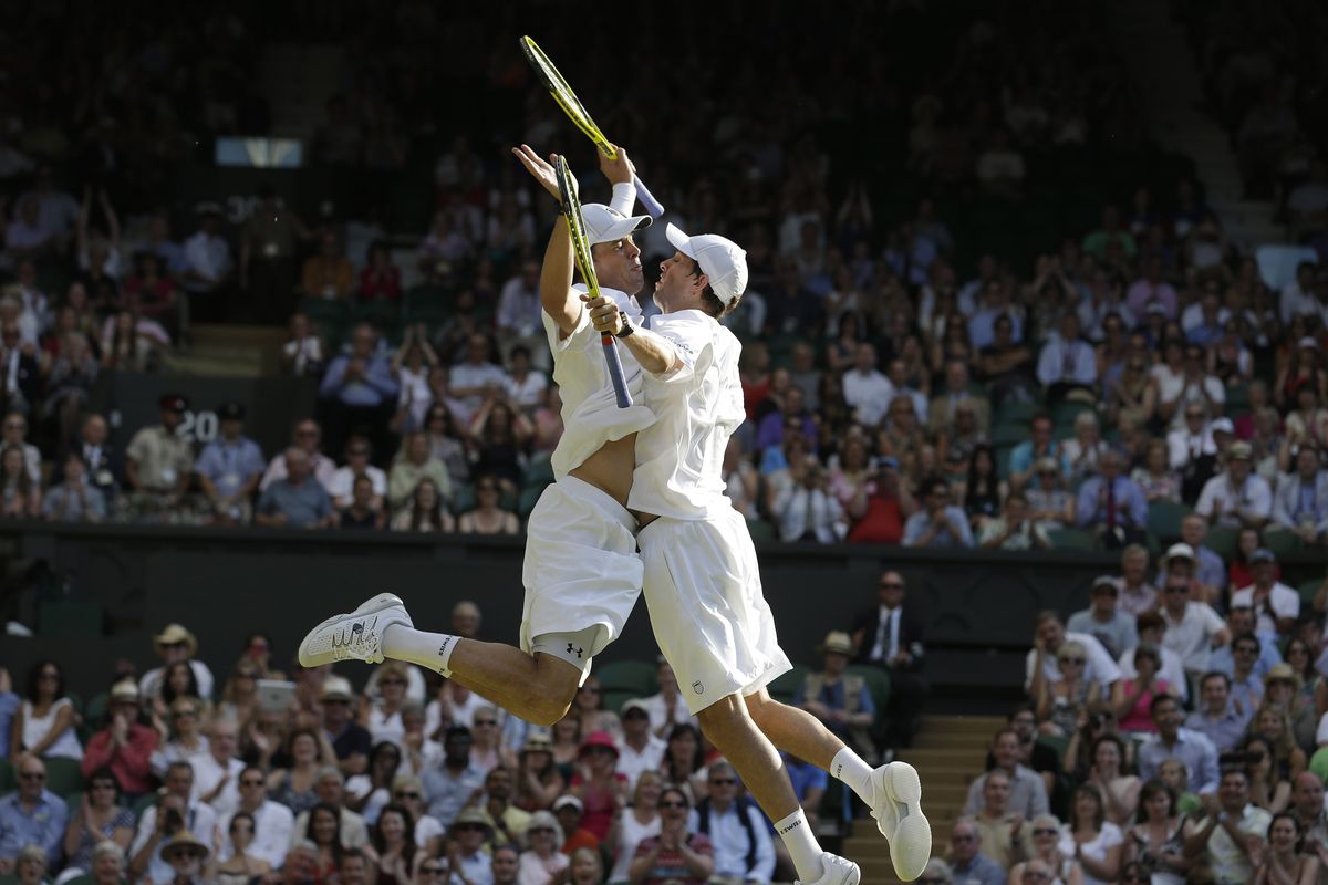 American twin brothers Bob and Mike Bryan do the ‘Bryan Bump’ after winning men’s doubles title at Wimbledon on Saturday. (Associated Press)