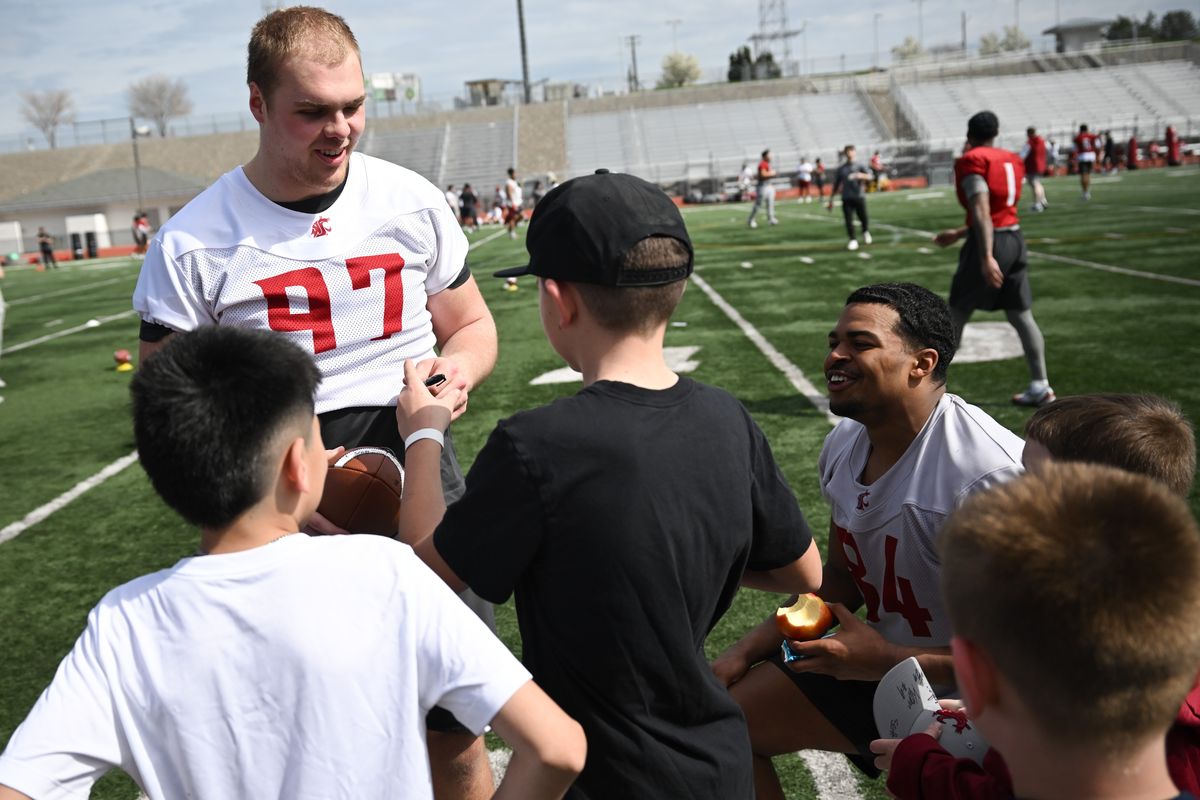 Washington State Cougars defensive end Josh Wedel (97) and defensive end Malachi Wrice (84) smile as they sign autographs for young fans after a spring football practice on Saturday, Mar 28, 2026, at Edgar Brown Memorial Stadium in Pasco, Wash. (Tyler Tjomsland/The Spokesman-Review)