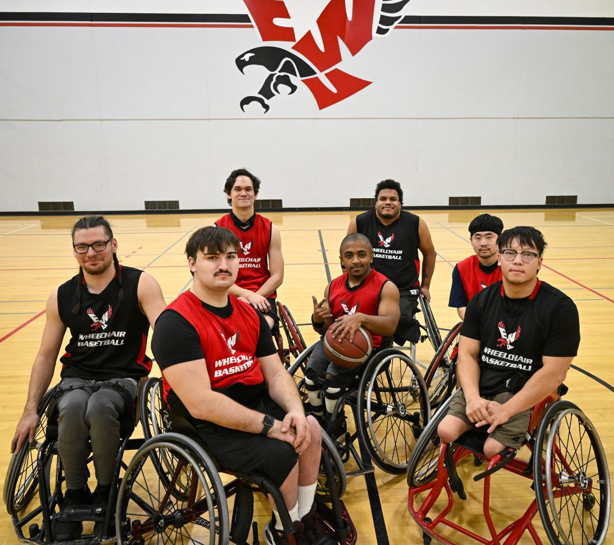Most of the Eastern Washington University wheelchair basketball team gather recently at center court after practice in a gym at EWU. They are Augustine Culley, left, Tyler Jenkins, Benjamin Belino, Brenden Williams, Jeffer Ward, Samuel Hahn and Mike Lucas. Not shown: player Liam Frobisher.  (Jesse Tinsley/THE SPOKESMAN-REVEWI)