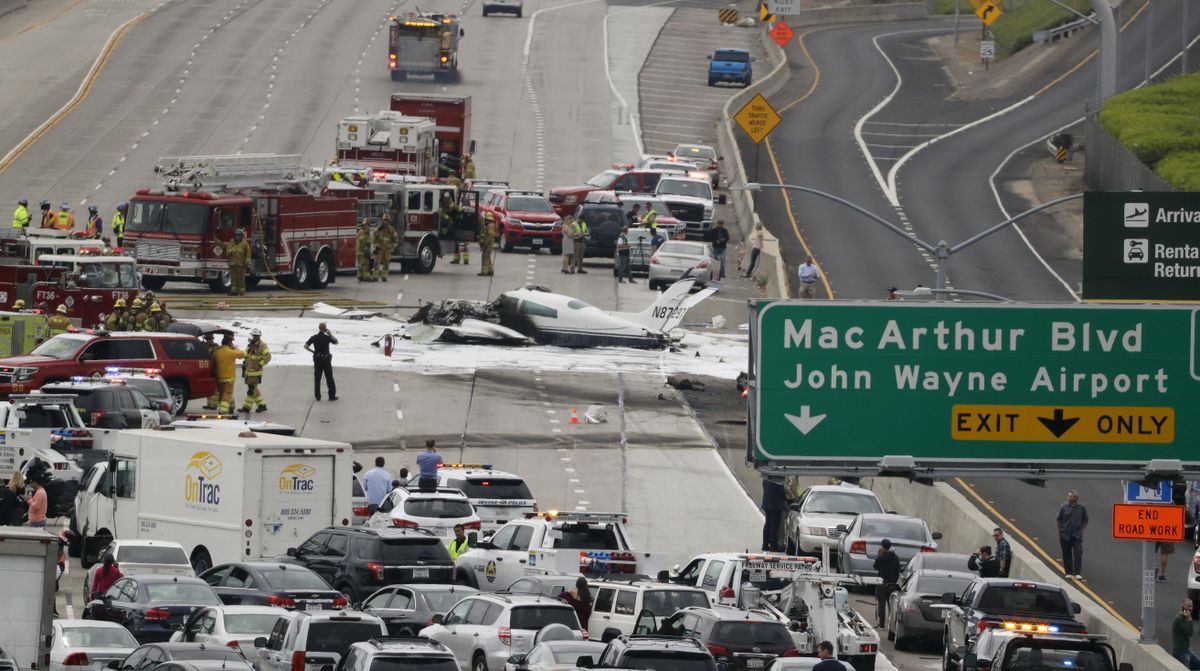Emergency responders gather round the crash of a Cessna 310 aircraft on Interstate 405, just short of a runway at John Wayne Airport in Costa Mesa, Calif., Friday, June 30, 2017. Two people were injured in the small plane crash. (Chris Carlson / Associated Press)