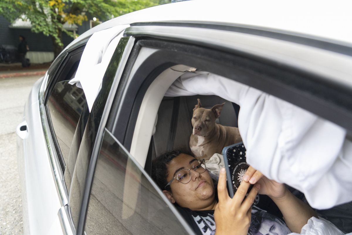 Cierra Audet and her dog, Coda, inside the car that they sleep in with Cierra’s mother, Chrystal Audet, in a SafePark parking lot outside a United Methodist Church on Aug. 28 in Kirkland, Wash. The family is among a growing cohort of working Americans living out of their cars.  (RUTH FREMSON)