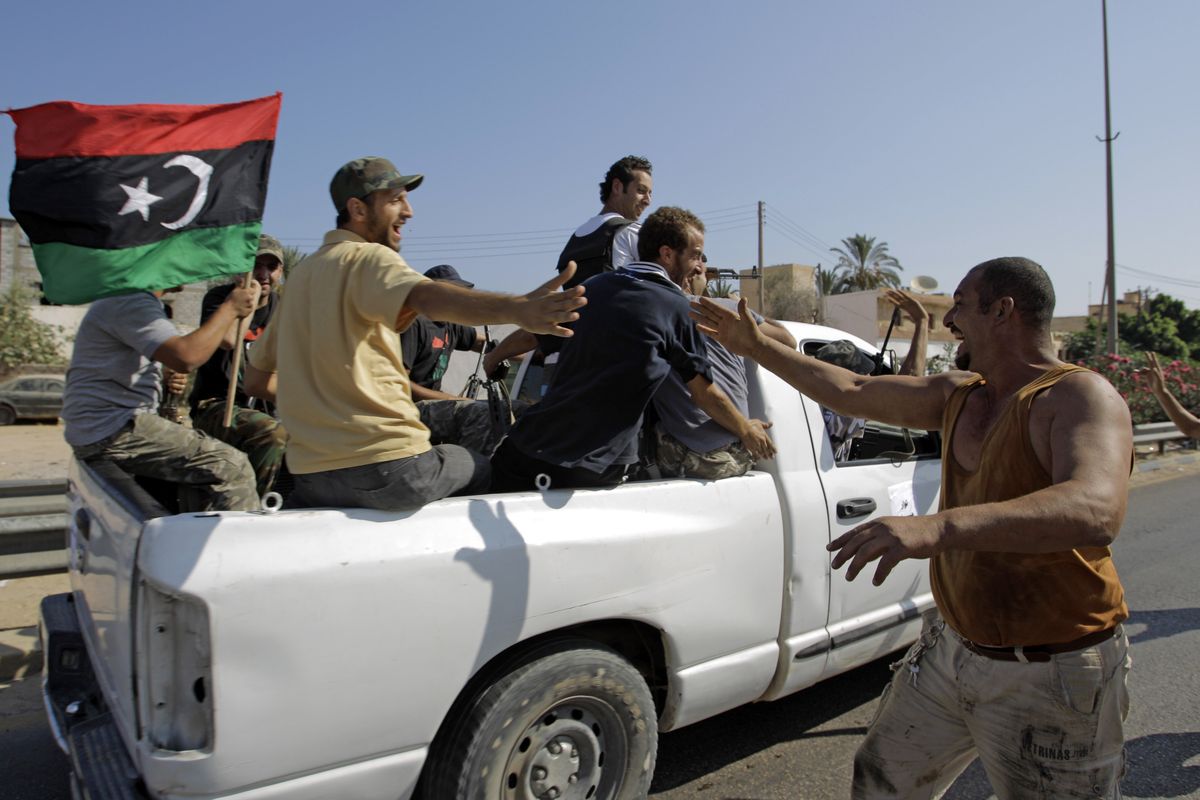 Local residents greet advancing rebel fighters on outskirts of Tripoli, Libya, on Monday, Aug. 22, 2011. Libyan rebels claimed to be in control of most of the Libyan capital on Monday after their lightning advance on Tripoli heralded the fall of Moammar Gadhafi