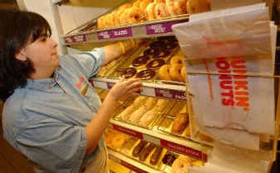 
Manager Kim Rolli restocks racks of donuts at a Boston branch of Dunkin' Donuts on Thursday. The 55-year-old franchise chain is trying to hold onto its core customers while winning over some of the Starbucks crowd. 
 (Associated Press / The Spokesman-Review)