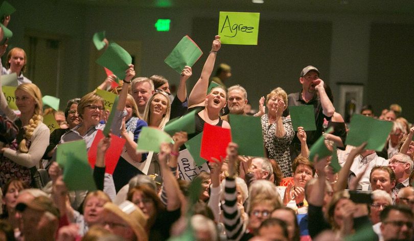 Attendees hold up green paper in solidarity with a speaker who asked a question during a town hall at Meridian Middle School in Meridian, Idaho, Wednesday, April 19, 2017. Idaho's Republican U.S. Rep. Raul Labrador is holding a town hall, the first of the state's congressional delegation to do so since the November election. (Kyle Green / Idaho Statesman via AP)