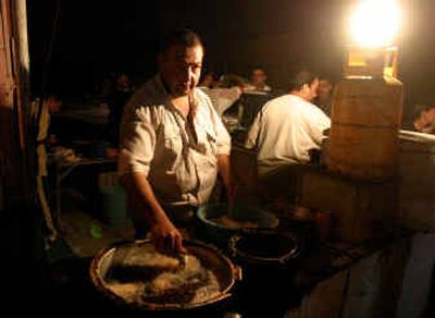 
Mutaz Ismael cooks Friday under light from a generator in Baghdad, Iraq. Electricity in Baghdad is at less than half prewar levels.
 (Associated Press / The Spokesman-Review)