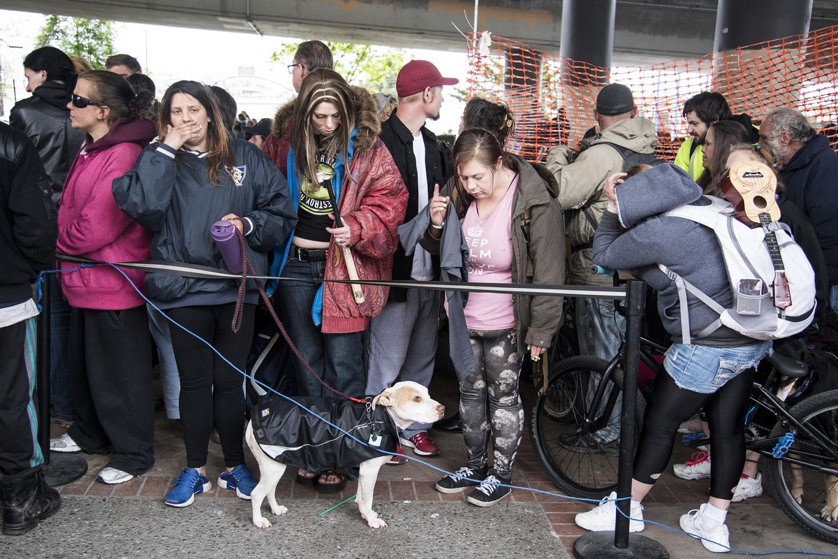 The homeless and the hungry wait patiently in a long line for the Blessings Under the Bridge dinner to be served Wed., May 17, 2017, under the Interstate 90 overpass. (Colin Mulvany / The Spokesman-Review)