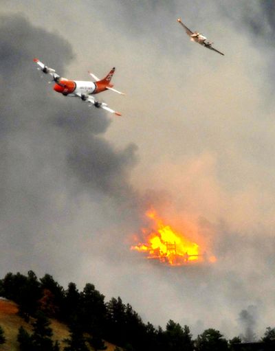 A spotter plane and large slurry bomber pass over a burning home in Boulder, Colo., on Tuesday. The plume from the fire could be seen in Wyoming, 90 miles north.  (Associated Press)