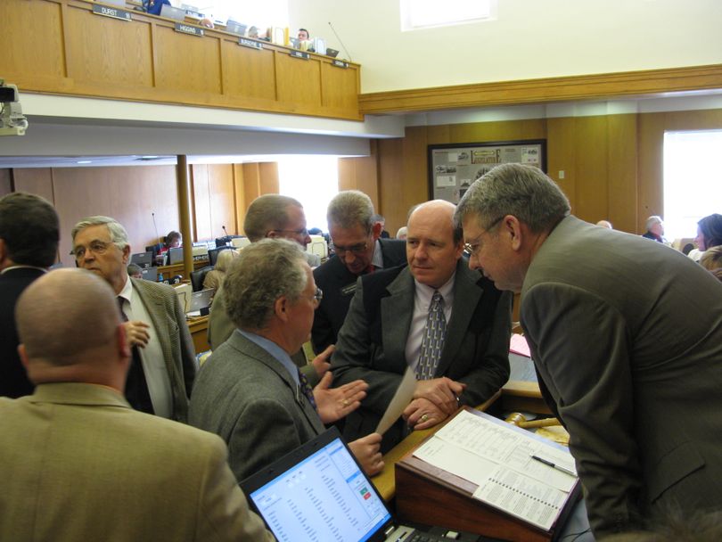 House majority and minority leaders huddle at the speaker's desk to discuss procedural issues, during a brief break in the debate on legislation to cut funding for public school teacher salaries by freezing movement on the salary grid for a year. Minority Leader John Rusche, D-Lewiston, left, talks to House Education Chairman Bob Nonini, R-Coeur d'Alene, House Majority Leader Mike Moyle, R-Star, and House Speaker Lawerence Denney, R-Midvale, right. (Betsy Russell / The Spokesman-Review)