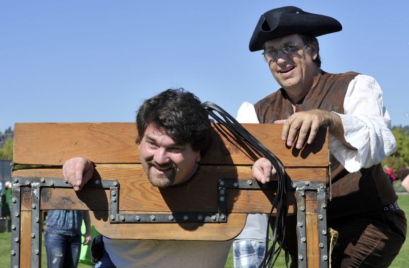 Rob West, 41, of Hillyard, poses in the stocks as his son, Jasper, photographed him with John Brooks, of Cheney, playing a sheriff. The display was provided by the Living History Players at Valleyfest, Sept. 25, 2010 at Mirabeau Point Park.  (Dan Pelle / The Spokesman-Review)