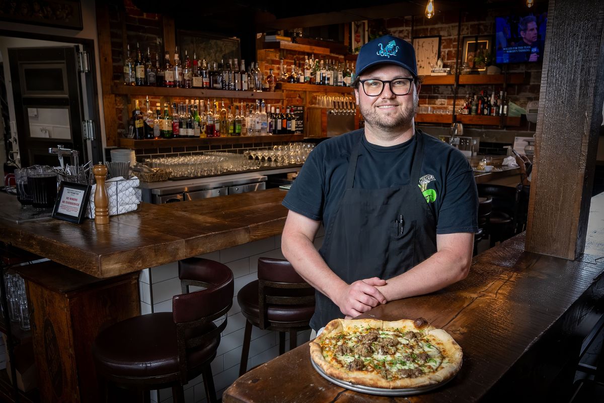 Taylor Rainwater, owner of the Temple Tavern is photographed with the Seeker, a pizza made with extra-virgin olive oil, fresh mozzarella, Gorgonzola cheese, meatballs, caramelized onion, balsamic reduction and parsley. (COLIN MULVANY/The Spokesman-Review)