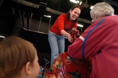 
Kristina Brennan hands a large sack of toys to one of 74 foster families  who came to the annual foster family Christmas party Saturday at Post Falls High School. 
 (Jesse Tinsley / The Spokesman-Review)
