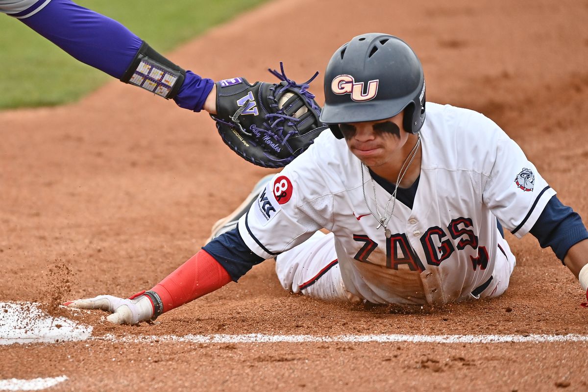 Gonzaga this baseman Connor Coballes (4) dives under the tag attempt of Washington first baseman Coby Morales (26) during a college baseball game at Patterson Baseball Complex and Coach Steve Hertz Field on Monday May 2, 2022 in Spokane WA.  (James Snook/For The Spokesman-Review)