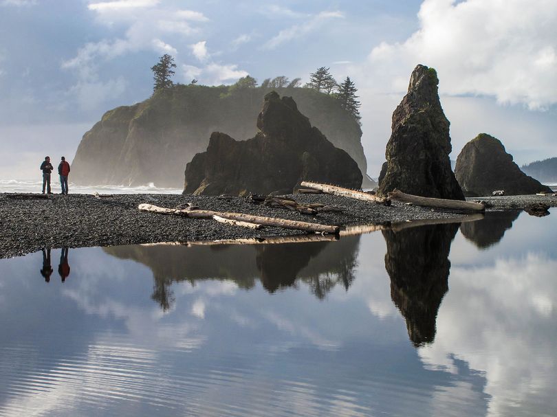 Olympic features: Hikers explore drift wood and rock “haystacks,” two of the signature attractions at Ruby Beach on the Olympic Peninsula south of Forks, Washington, in mid-May, 2015. The beach is named for the ruby-like crystals in the sand. Ruby Beach is the northernmost of the southern beaches in Olympic National Park.