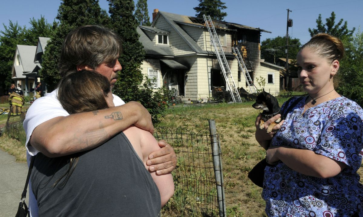 Roger Bowman comforts his girlfriend, Cindi Jackson, after a fire gutted their second-floor apartment Wednesday.  Jackson’s daughter-in-law, Angela Jackson, holds Cindi’s dog, Fernando. (Dan Pelle / The Spokesman-Review)