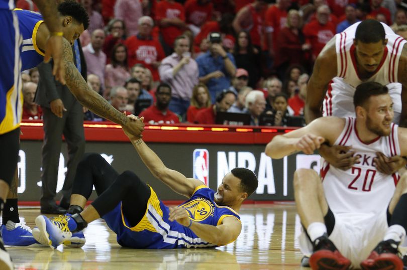 In this Sunday photo, Golden State Warriors guard Stephen Curry (30) is helped up after being injured on the final play during the first half of Game 4 in the first round of the NBA playoff series against the Houston Rockets. (Karen Warren / Associated Press)